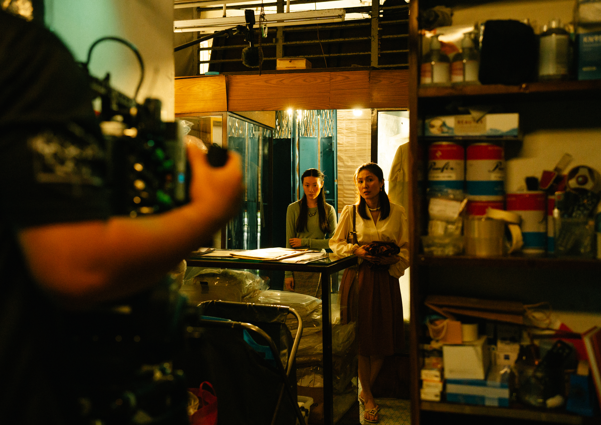LASALLE film students on a set shoot, capturing a dramatic scene inside a cluttered shop space with warm lighting.