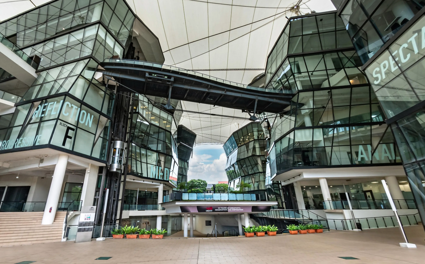 View of LASALLE’s McNally Campus with angular glass buildings, skybridge and white tensile roof canopy.