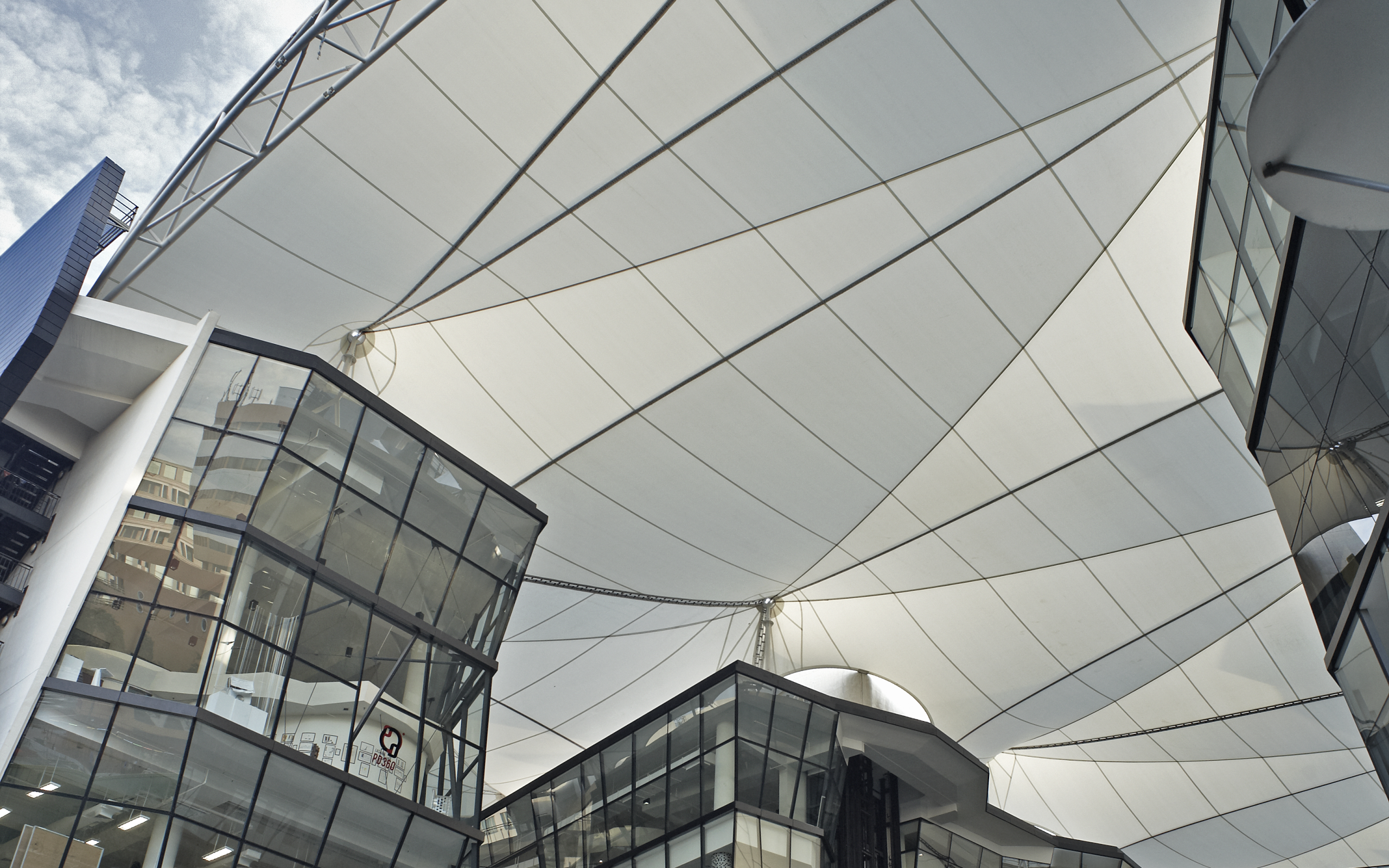 Tensile roof canopy over LASALLE’s campus with dramatic lines and angles that frame the building’s glass façades and sky above.