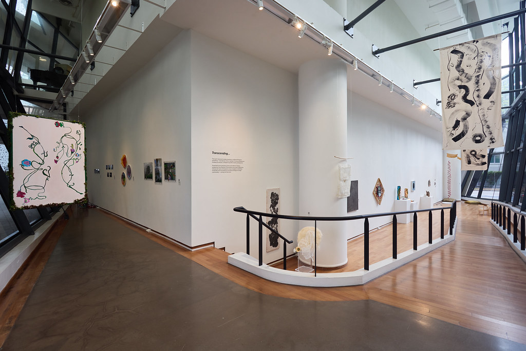 LASALLE gallery corridor with hanging scrolls, wall-mounted artworks and sculptures displayed along white walls and glass windows.