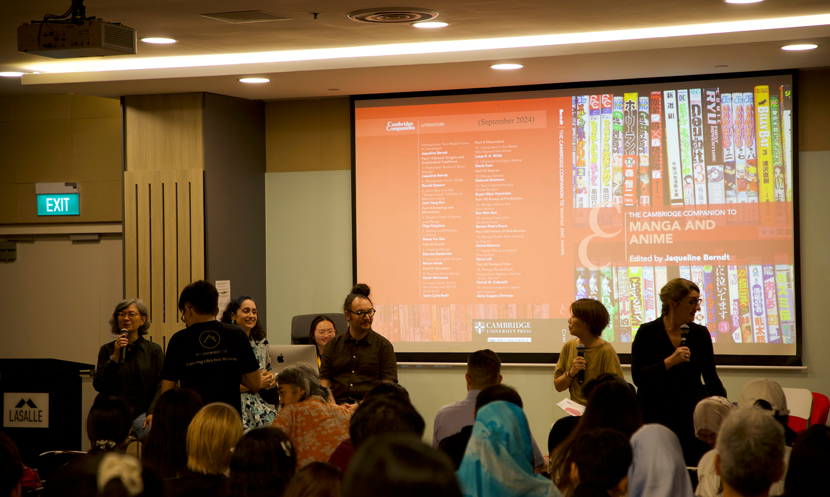 LASALLE lecture hall event with speakers discussing manga and anime, as a presentation slide is projected to a full audience.